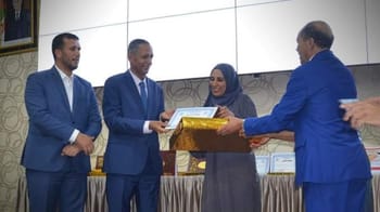 Femme recevant un diplôme lors d'une cérémonie officielle à Batna.