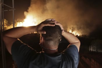 Homme observant un incendie de forêt en Algérie la nuit.