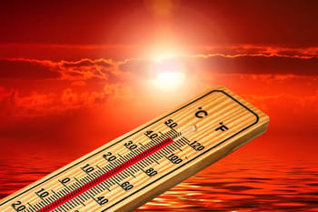 Thermomètre montrant la température avec un coucher de soleil en arrière-plan.
