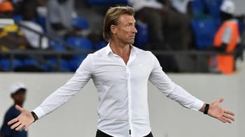 Homme en chemise blanche, gesticulant sur le terrain.