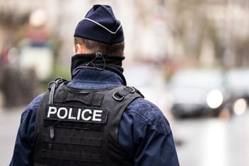 Policier en uniforme dans une rue urbaine, vue de dos.