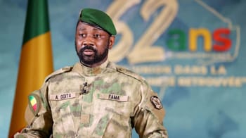 Officier militaire en uniforme avec drapeau national en arrière-plan.
