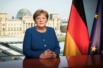 Angela Merkel lors d'une conférence avec drapeaux allemand et européen.