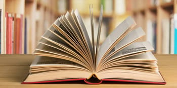 Livre ouvert avec pages tournées, bibliothèque en arrière-plan.