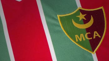 Logo du Mouloudia d’Alger avec couleurs vert, rouge et jaune.