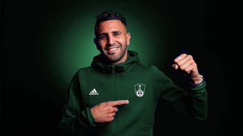 Mahrez souriant en tenue de football verte avec logo de son équipe.