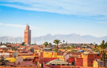 Vue de Marrakech avec la Koutoubia et les montagnes en arrière-plan.