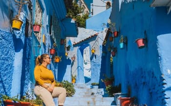 Rue colorée de Chefchaouen avec murs bleus et pots de fleurs.
