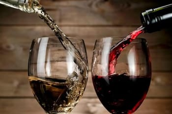 Verres de vin rouge et blanc en train d'être remplis.