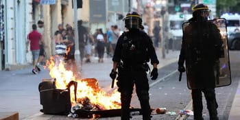Policiers en tenue anti-émeute face à un incendie en ville.