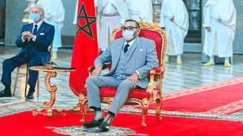 Le roi du Maroc lors d'une cérémonie officielle avec drapeau BRICS en arrière-plan.
