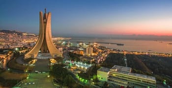 Vue panoramique d'Alger avec la basilique Notre-Dame d'Afrique au coucher du soleil.