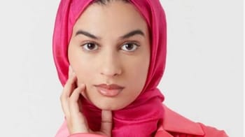 Jeune femme voilée avec hijab rose, regard direct, visage clair.