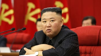 Kim Jong-un, leader nord-coréen, lors d'une réunion avec drapeaux rouges en arrière-plan.