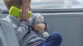 Jeune garçon de 7 ans parlant au téléphone avec une mère à la gare.