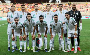 Groupe de joueurs algériens en tenue de match sur le terrain.