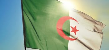 Drapeau algérien flottant au vent avec soleil en arrière-plan.