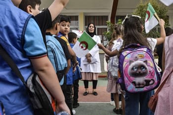 Enfants algériens avec drapeaux lors d'une activité scolaire.