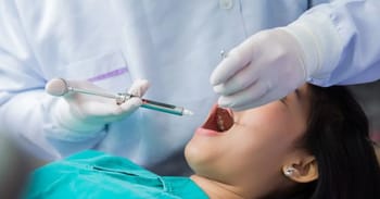 Dentiste administrant une anesthésie dentaire à une patiente.