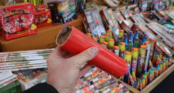 Main tenant un pétard rouge dans un magasin de feux d'artifice.