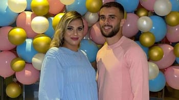 Jeune couple souriant devant un mur de ballons multicolores.
