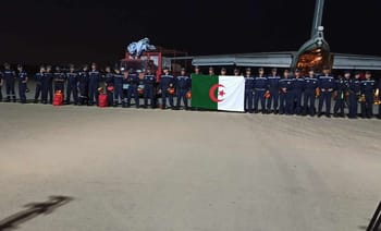 Groupe de personnel militaire algérien avec drapeau algérien et avions en arrière-plan.