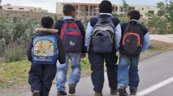 Groupe d'élèves avec sacs à dos marchant dans un environnement extérieur.