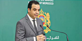 Homme en costume gris parlant lors d'une conférence au Maroc.