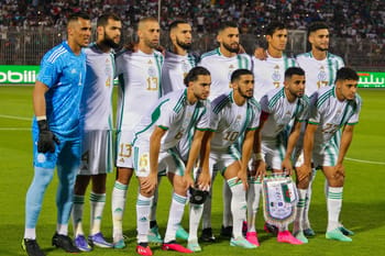 Groupe d'athlètes algériens en tenue de match sur le terrain.