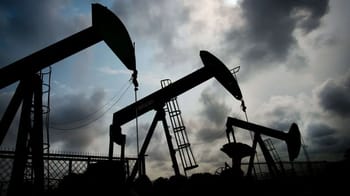 Puits de pétrole en silhouette sous ciel nuageux.