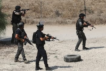 Policiers armés en opération dans un terrain désertique.