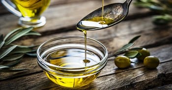 Huile d'olive versée dans une cuillère avec un bol à côté.