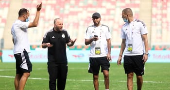 Entraîneurs de football discutant sur le terrain.