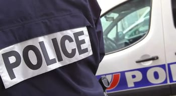 Agent de police en uniforme près d'une voiture de police en France.