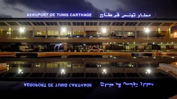 Vue nocturne de l'aéroport de Tunis Carthage avec signalisation en français et arabe.