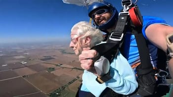 Femme âgée sautant en parachute avec un instructeur dans le ciel bleu.