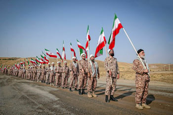 Soldats iraniens en uniforme avec drapeaux lors d'une parade militaire.