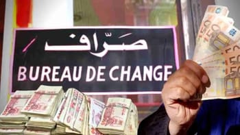 Personne tenant des billets de banque devant un bureau de change en Algérie.