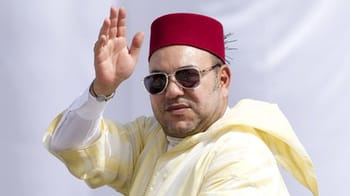 Homme portant fez, lunettes de soleil, saluant avec la main.