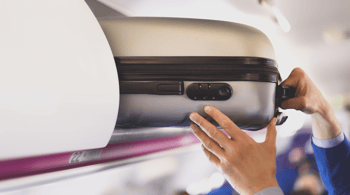 Bagage cabine en avion prêt à être rangé dans le compartiment supérieur.