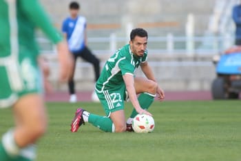 Ismaël Bennacer en tenue verte, prêt à jouer au football sur le terrain.