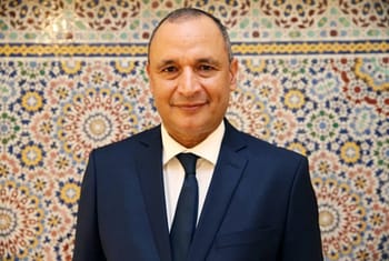 Homme en costume avec fond décoratif marocain coloré.