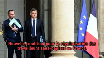 Deux hommes en costume devant un bâtiment avec drapeaux français et européen.