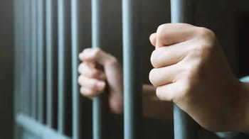 Mains d'un détenu tenant les barreaux d'une cellule de prison.