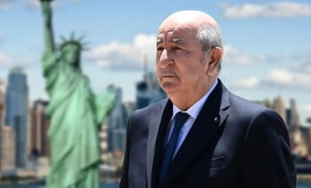 Homme en costume devant la Statue de la Liberté à New York.