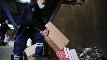 Agents de police inspectant des colis de tabac illégal.