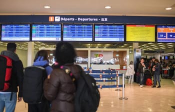 Tableau d'affichage des départs à l'aéroport avec voyageurs.
