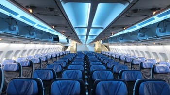 Cabine d'avion vide avec sièges bleus et éclairage moderne.