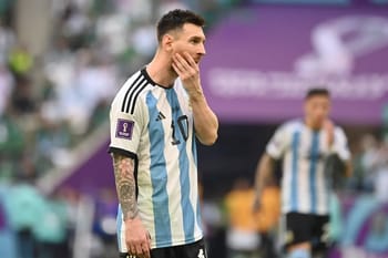 Lionel Messi en tenue argentine, pensif sur le terrain de football.