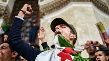 Jeune manifestant criant avec un drapeau algérien lors d'une protestation.